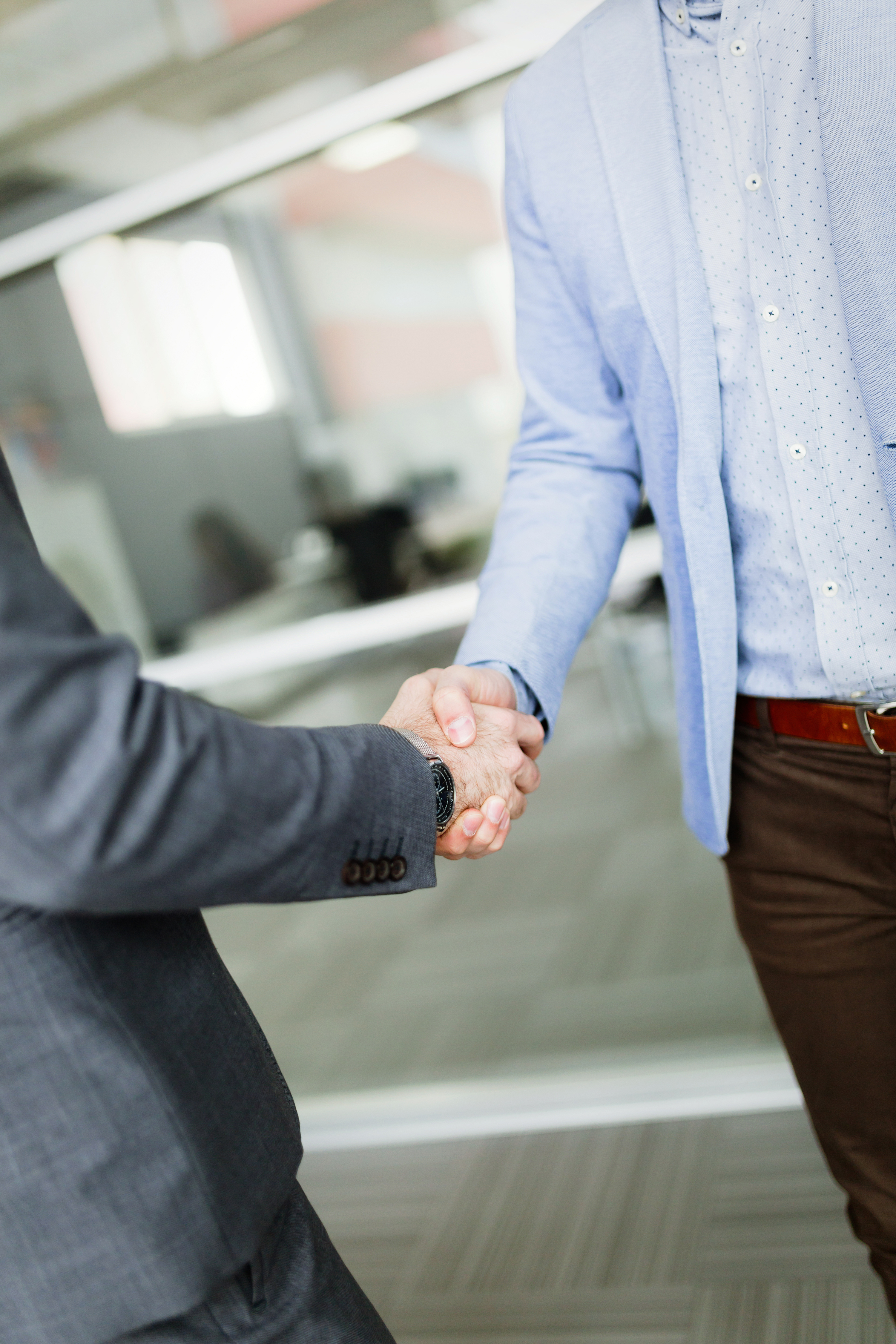 Nahaufnahme von zwei Männer in Anzügen, die sich energisch die Hand schütteln