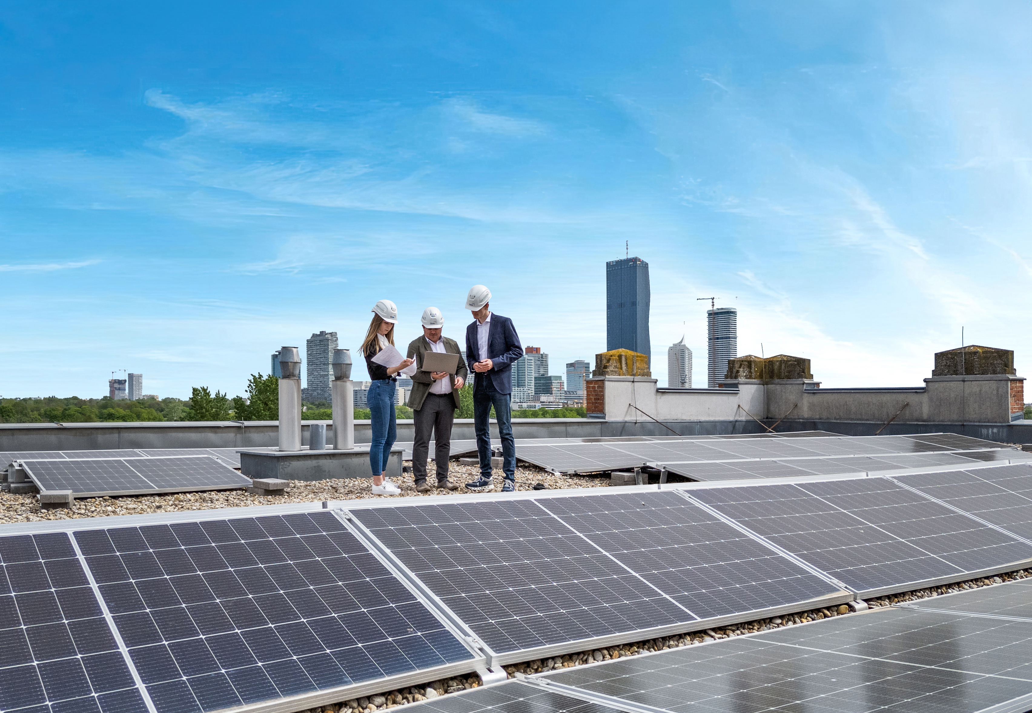 Drei ÖSW Mitarbeiter sitzen auf dem Dach der Zweigstelle am Handelskai und unterhalten sich angeregt